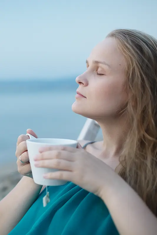 Eine Frau entspannt und trinkt einen Tee dank der Mütterpflege von Anne Ellrodt
